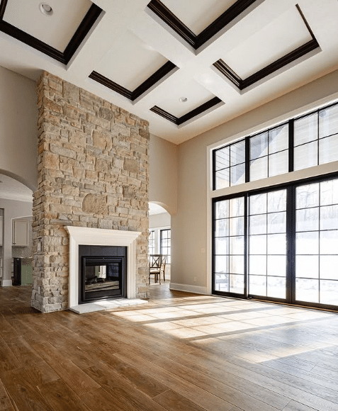 A large living room with high ceilings and a fireplace in a tall stone accent wall