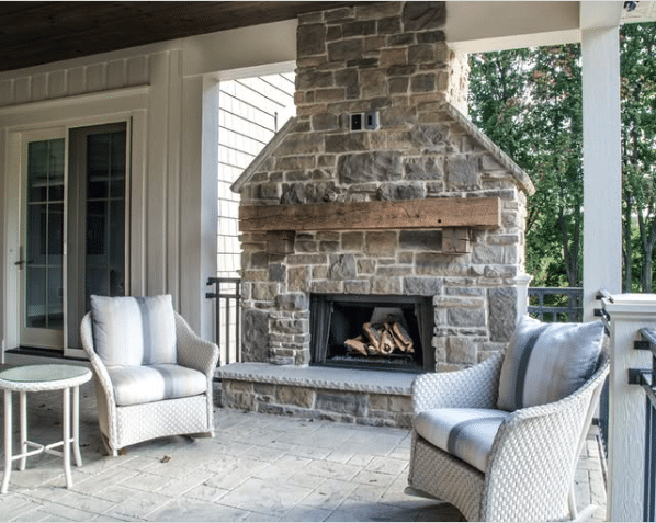 Outdoor fireplace with a stone wall and wooden mantle